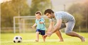 Healthy child happily playing soccer/football with his father