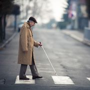 Blind man crossing street with walking stick