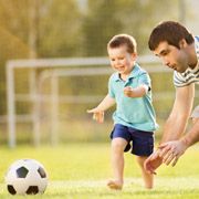 Healthy child happily playing soccer/football with his father