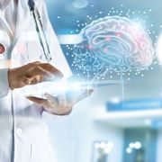 Doctor on laptop next to image of computer brain